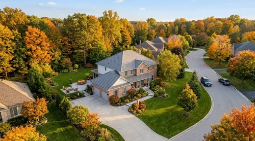 An aerial view of a neat suburban home nestled among golden autumn trees, creating a peaceful and inviting atmosphere.
